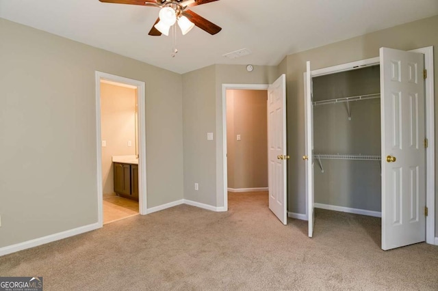 unfurnished bedroom featuring ceiling fan, baseboards, light carpet, a closet, and ensuite bath