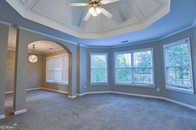 carpeted spare room with a raised ceiling, arched walkways, a healthy amount of sunlight, and crown molding