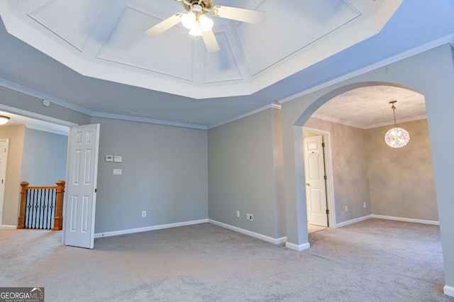 empty room with ceiling fan, baseboards, carpet, ornamental molding, and arched walkways