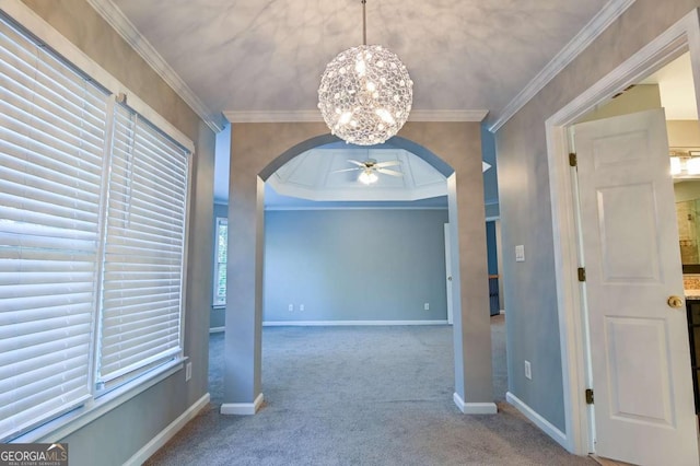 unfurnished dining area with baseboards, arched walkways, ornamental molding, carpet flooring, and ceiling fan with notable chandelier