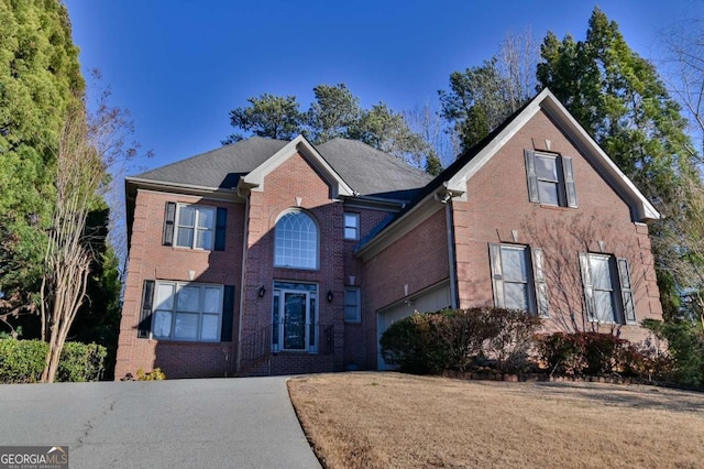 traditional home featuring brick siding, driveway, and a garage