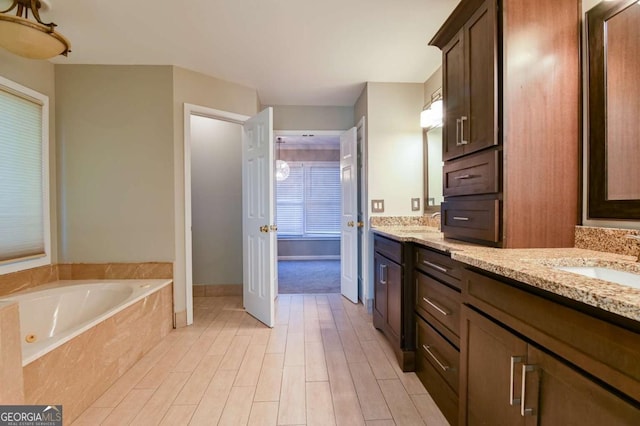 bathroom featuring a garden tub, wood finished floors, double vanity, and a sink