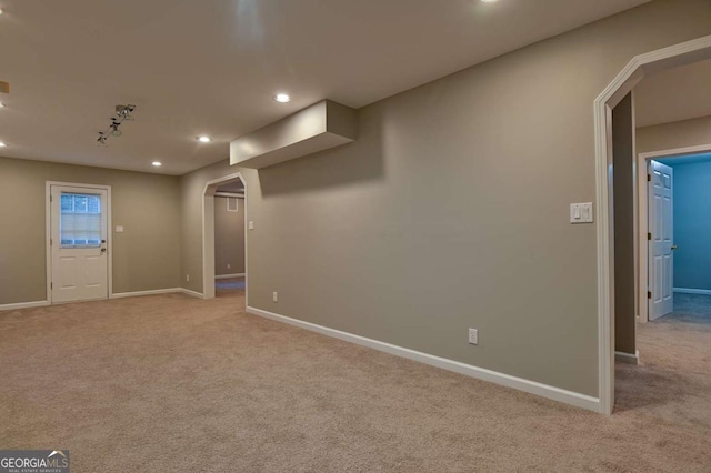 interior space featuring recessed lighting, light colored carpet, arched walkways, and baseboards