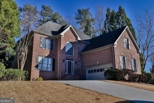 traditional-style home featuring brick siding, driveway, a front yard, and a garage