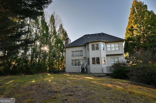 back of property featuring a lawn and a chimney