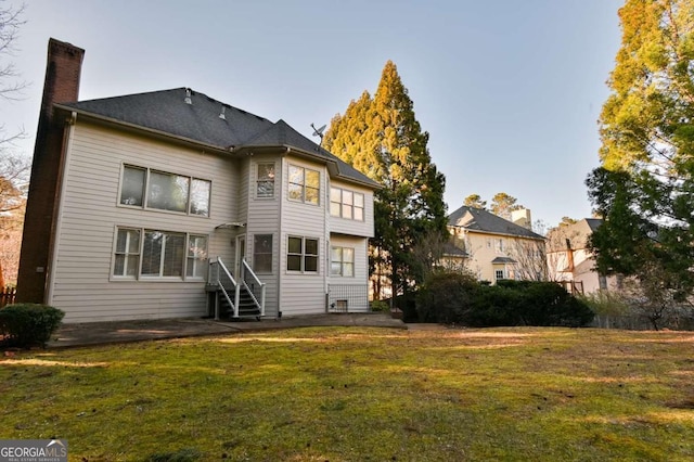 back of house with a yard, a patio area, and a chimney