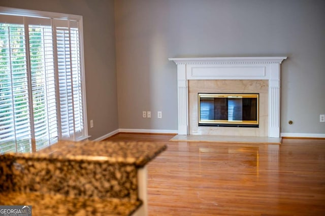 unfurnished living room featuring a fireplace, baseboards, and wood finished floors