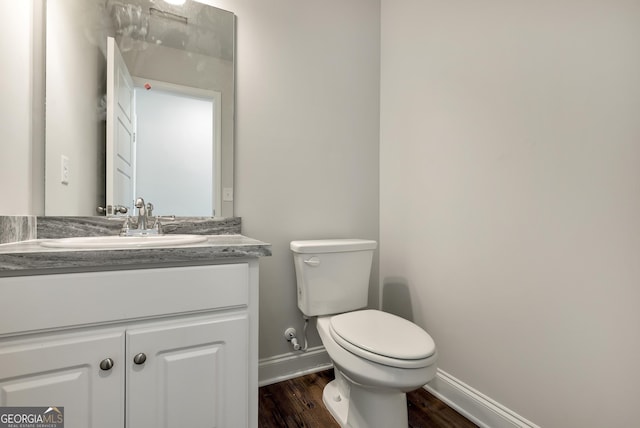 bathroom with toilet, baseboards, wood finished floors, and vanity