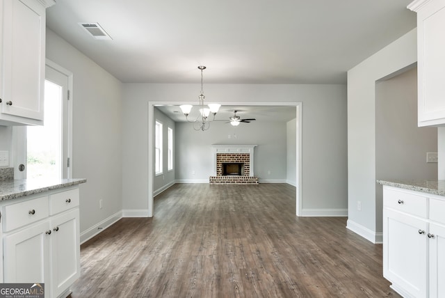 unfurnished living room with plenty of natural light, a fireplace, dark wood finished floors, and visible vents