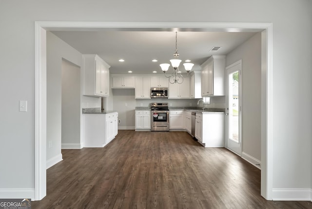 kitchen featuring visible vents, white cabinets, light stone counters, dark wood-style flooring, and stainless steel appliances