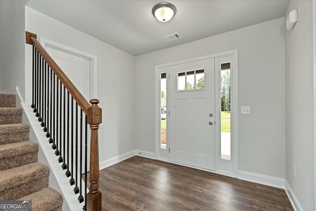 entryway with stairs, dark wood finished floors, visible vents, and baseboards