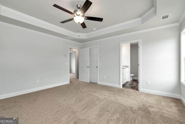 unfurnished bedroom with baseboards, visible vents, a raised ceiling, ornamental molding, and carpet flooring