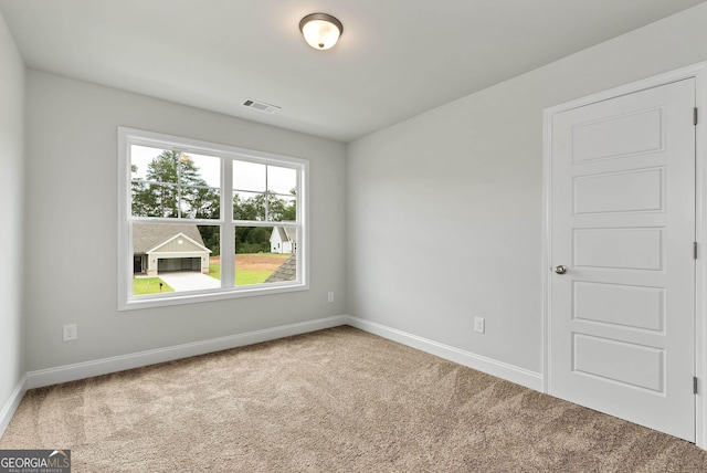 unfurnished room with carpet, visible vents, and baseboards