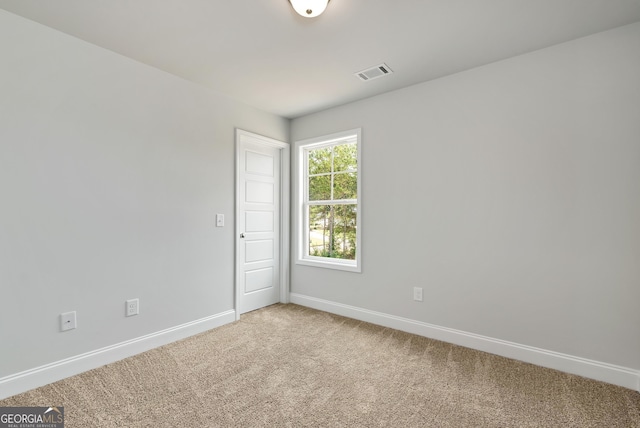 unfurnished room with visible vents, light carpet, and baseboards