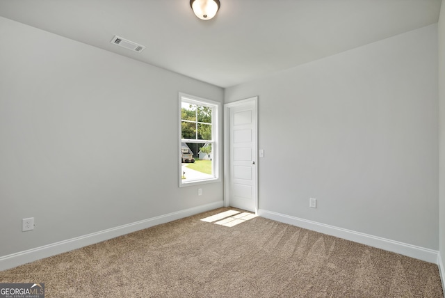 carpeted spare room with visible vents and baseboards