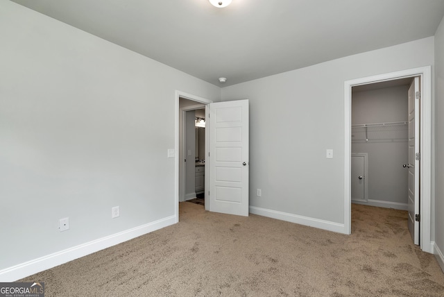 unfurnished bedroom featuring a spacious closet, a closet, carpet, and baseboards