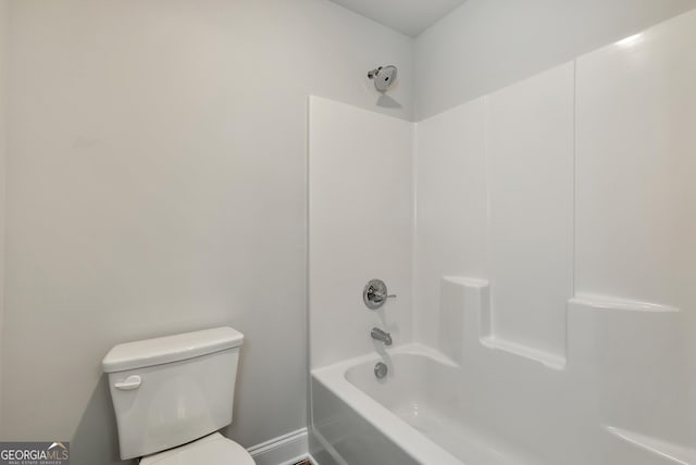 bathroom featuring toilet, baseboards, and shower / bathtub combination