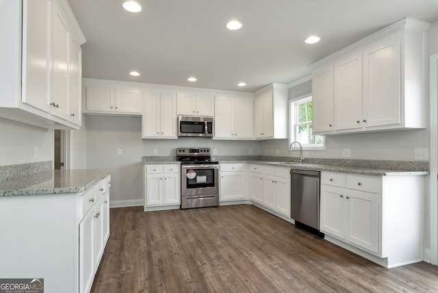 kitchen with dark wood-style flooring, stainless steel appliances, recessed lighting, white cabinets, and a sink