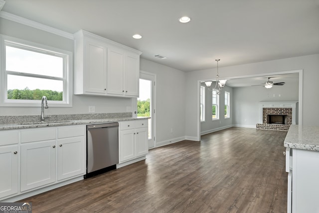 kitchen featuring plenty of natural light, stainless steel dishwasher, a fireplace, white cabinetry, and a sink