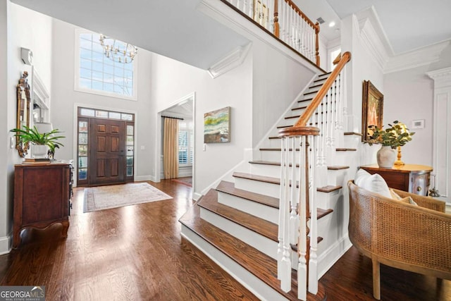 foyer featuring ornamental molding, a high ceiling, baseboards, and wood finished floors