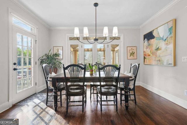 dining space with baseboards, ornamental molding, a chandelier, and wood finished floors