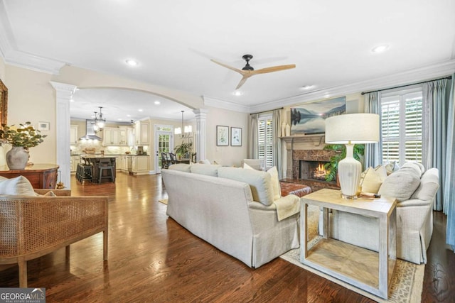 living room featuring ornate columns, plenty of natural light, arched walkways, and ceiling fan