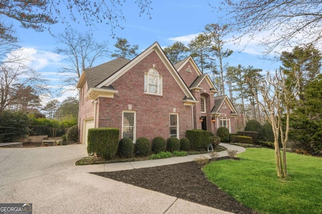 traditional-style home featuring a garage, a shingled roof, concrete driveway, a front lawn, and brick siding