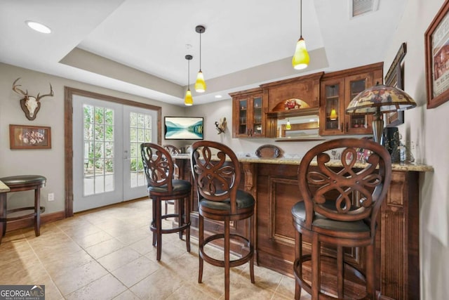 bar with bar area, visible vents, french doors, a raised ceiling, and decorative light fixtures