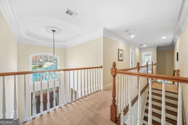 hallway with visible vents, ornamental molding, an inviting chandelier, carpet flooring, and an upstairs landing