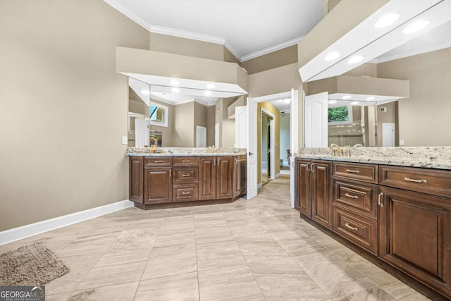 full bathroom with ornamental molding, two vanities, a sink, and baseboards