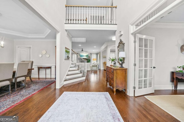 entryway with stairs, crown molding, and wood finished floors