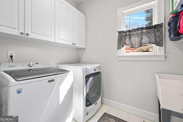 clothes washing area featuring cabinet space, light tile patterned floors, baseboards, and washer and clothes dryer