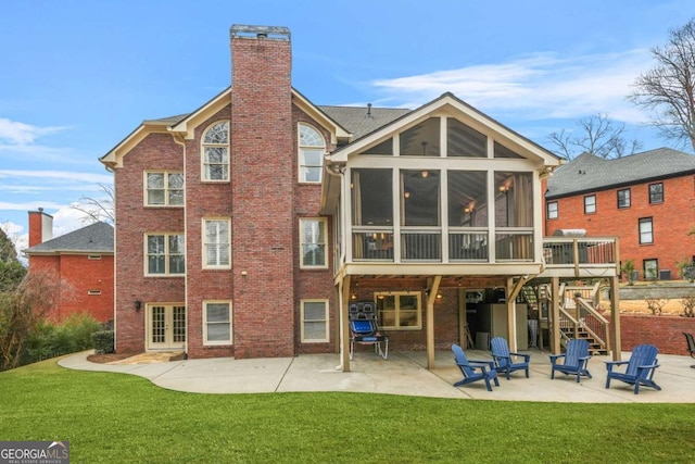 rear view of property with a sunroom, a patio area, a chimney, and brick siding