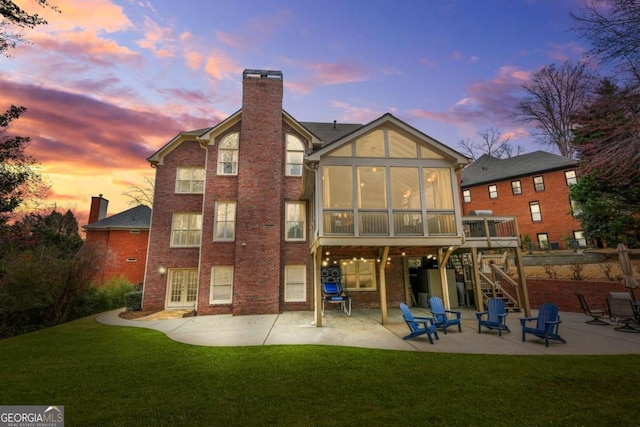 rear view of house with a patio area, stairs, a chimney, and a sunroom