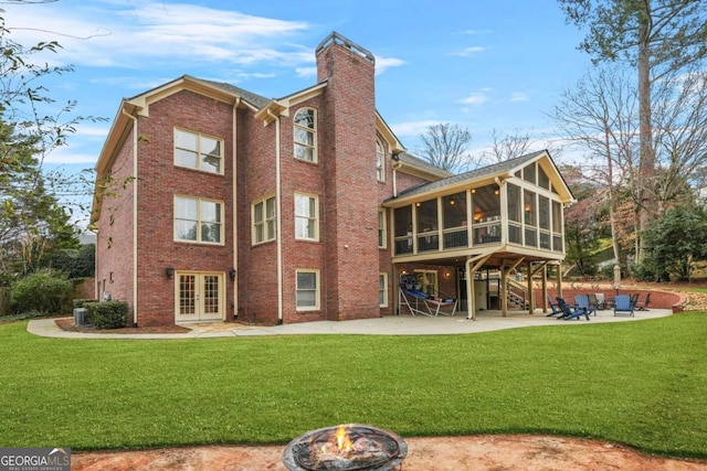 back of house with an outdoor fire pit, a sunroom, french doors, a chimney, and a patio area