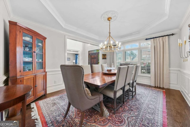 dining space featuring a wainscoted wall, a notable chandelier, a raised ceiling, a decorative wall, and ornamental molding