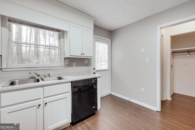 kitchen featuring wood finished floors, a sink, white cabinetry, black dishwasher, and light countertops