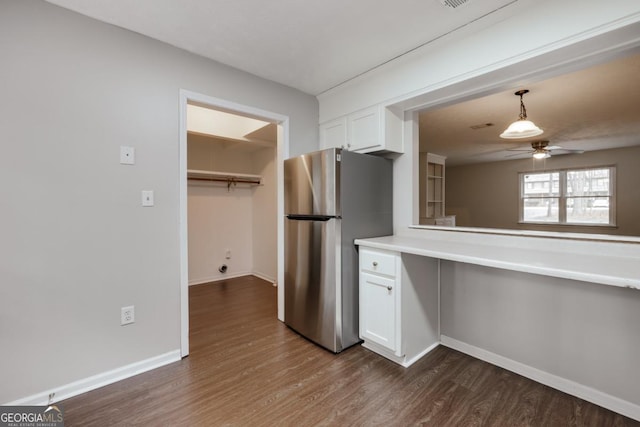 kitchen featuring baseboards, white cabinets, a ceiling fan, dark wood-style flooring, and freestanding refrigerator