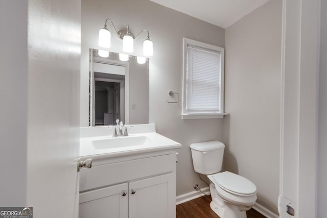 half bath featuring toilet, baseboards, wood finished floors, and vanity