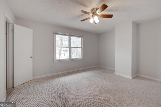 spare room featuring a textured ceiling, ceiling fan, carpet flooring, and baseboards