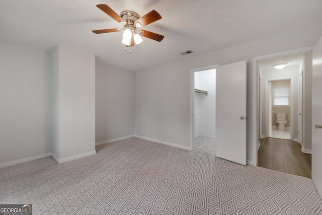 unfurnished bedroom featuring baseboards, visible vents, a ceiling fan, a walk in closet, and a closet