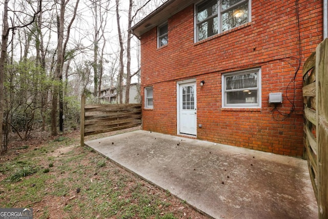 back of house featuring a patio area, brick siding, and fence