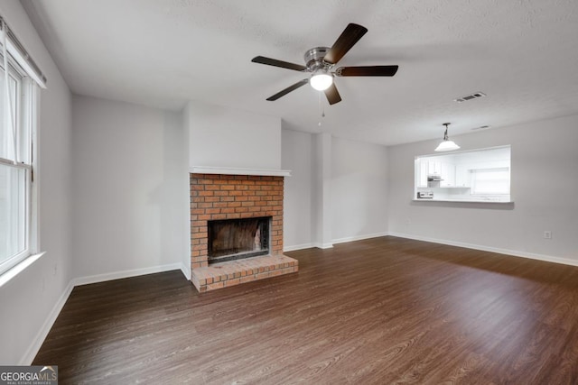 unfurnished living room with a fireplace, wood finished floors, visible vents, and baseboards