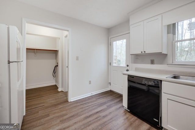 kitchen with light wood-type flooring, black dishwasher, white cabinets, and freestanding refrigerator