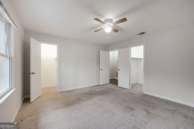 unfurnished bedroom featuring carpet floors, baseboards, visible vents, and a walk in closet