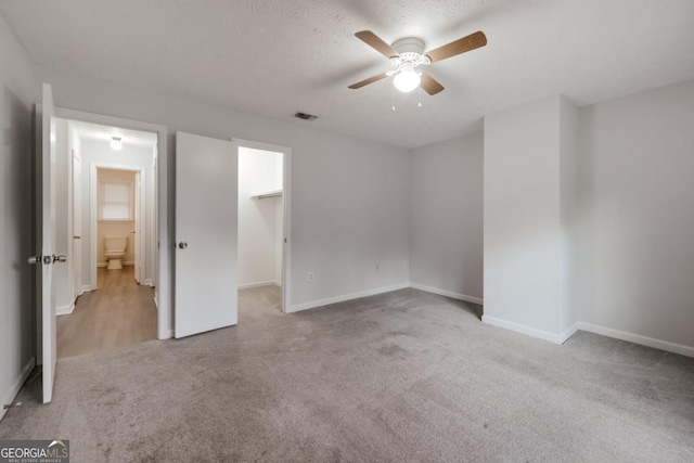 unfurnished bedroom featuring baseboards, carpet flooring, visible vents, and a walk in closet