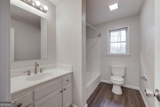 full bath featuring baseboards, toilet, shower / tub combination, wood finished floors, and vanity