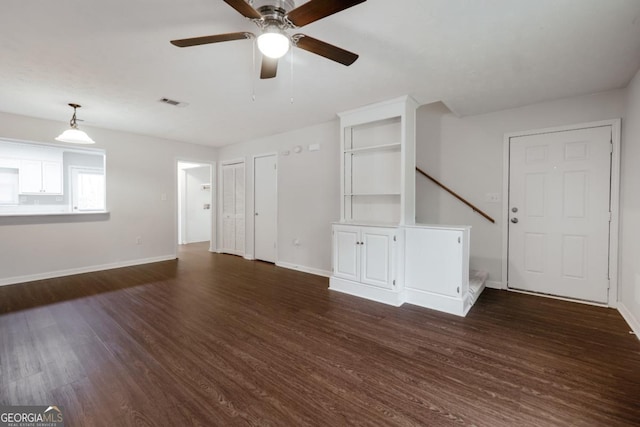 unfurnished living room with visible vents, baseboards, and dark wood-type flooring