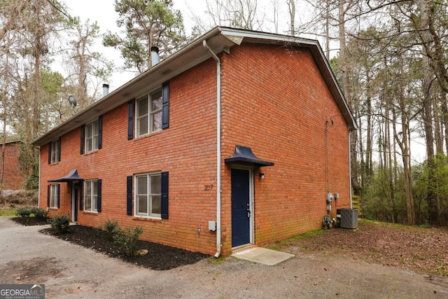 view of side of home with brick siding and central air condition unit