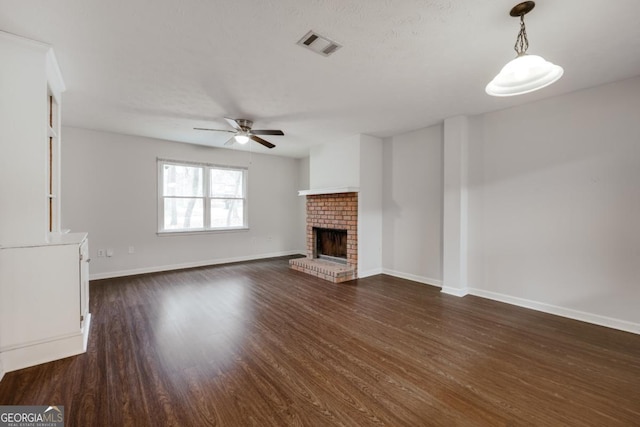 unfurnished living room with a fireplace, visible vents, a ceiling fan, baseboards, and dark wood-style floors